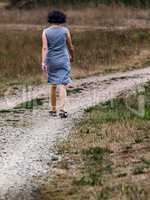 Woman is walking alone on dirt road