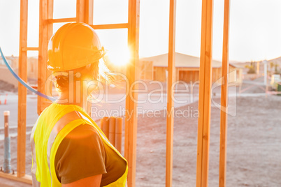 Female Construcion Worker Looking Out From New Home Framing