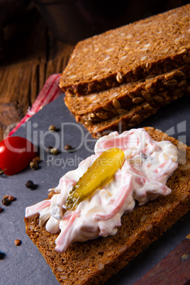 delicious spicy meat salad with cucumber on the black bread