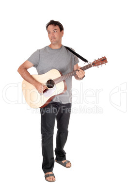 A tall man standing playing his guitar