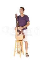 Man standing with his guitar behind a chair