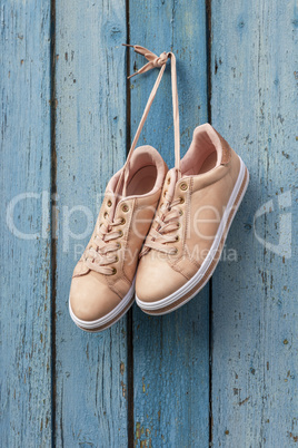 pair of beige female sports shoes hanging