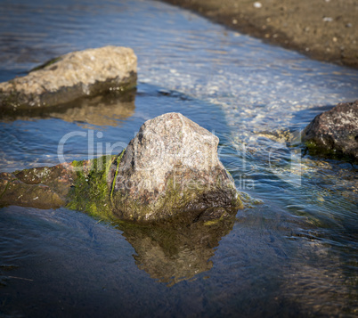 stone sticking out of the sea water summer day