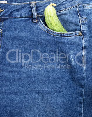 green cucumber lies in the front pocket of blue jeans