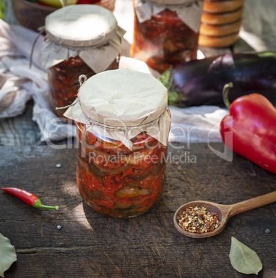 Canned eggplant slices in spicy vegetable sauce in glass jars