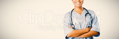 Smiling professional nurse with crossed arms wearing pink ribbon