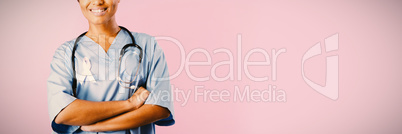 smiling nurse with crossed arms wearing pink ribbon