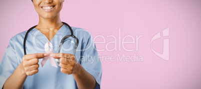 Smiling nurse holding breast cancer awareness pink ribbon with both hands