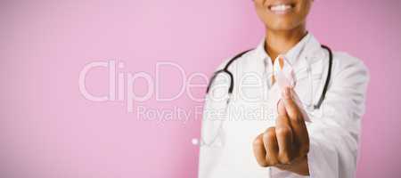 Smiling nurse holding a pink ribbon for breast cancer awareness