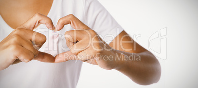 Women making heart with their fingers around pink ribbon