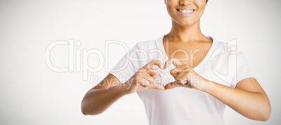 Smiling women making heart shape with their fingers around pink ribbon