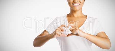 Smiling women making heart shape with their fingers around pink ribbon