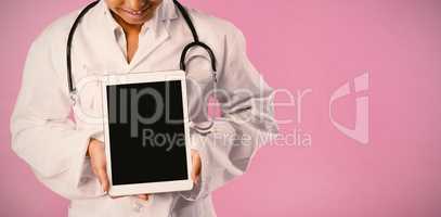 Smiling nurse wearing breast cancer awareness pink ribbon looks at her tablet
