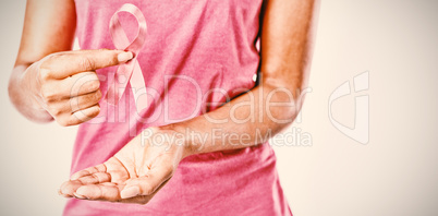 Woman holding ribbon between fingers for breast cancer awareness