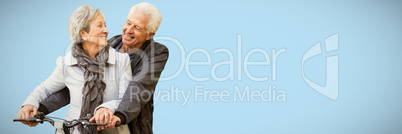 Composite image of senior couple sitting on bicycle while smiling