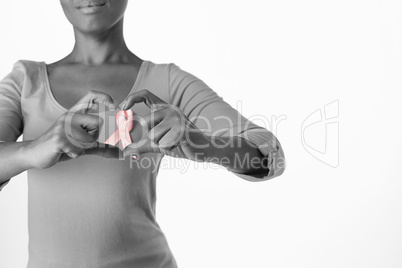 Women wearing pink shirt making heart with their fingers around pink ribbon