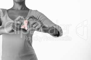 Women wearing pink shirt making heart with their fingers around pink ribbon