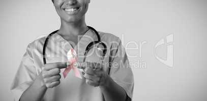 Smiling nurse holding breast cancer awareness pink ribbon with both hands