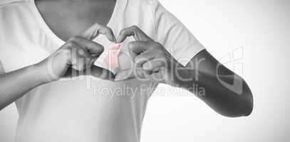 Women making heart shape with their fingers around pink ribbon