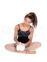 Woman in a ballet outfit sitting on the floor with her shoos