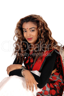 Smiling beautiful East Indian woman sitting in a dress