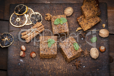 baked square slices of a pie whith nuts on a white wooden board,