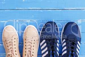 two pairs of male and female sports shoes on a blue wooden backg