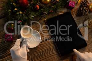 Santa Claus hands with coffee and tablet