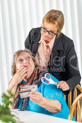 Financial Consultant Handing Scissors to Senior Lady Holding Cre