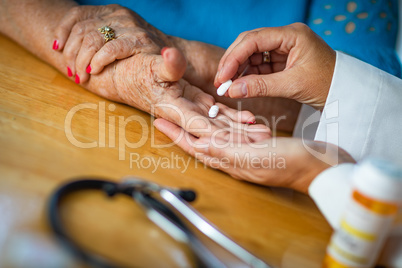 Doctor Handing Senior Adult Woman Medicine Pills