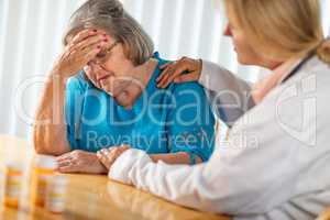 Female Doctor Consoling Distraught Senior Adult Woman