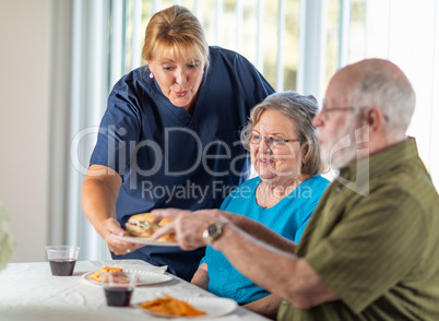 Female Doctor or Nurse Serving Senior Adult Couple Sandwiches