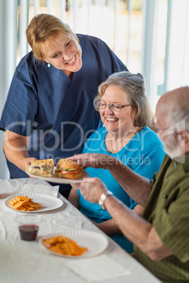 Female Doctor or Nurse Serving Senior Adult Couple Sandwiches at