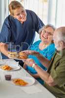 Female Doctor or Nurse Serving Senior Adult Couple Sandwiches