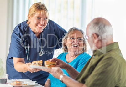 Female Doctor or Nurse Serving Senior Adult Couple Sandwiches at