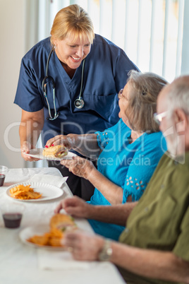 Female Doctor or Nurse Serving Senior Adult Couple Lunch