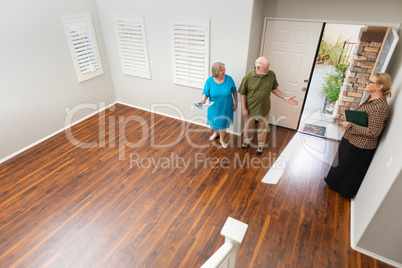 Female Real Estate Agent Showing Senior Adult Couple A New Home
