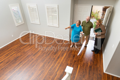 Female Real Estate Agent Showing Senior Adult Couple A New Home