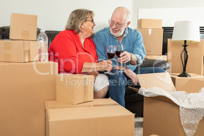 Senior Adult Couple Toasting Wine Glasses Surrounded By Moving B