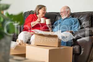 Tired Senior Adult Couple Resting on Couch with Cups of Coffee S