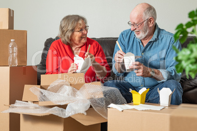 Senior Couple Enjoying Chinese Food Surrounded By Moving Boxes
