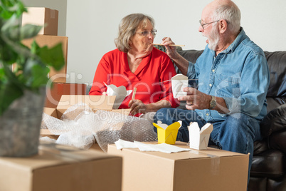 Senior Couple Enjoying Chinese Food Surrounded By Moving Boxes