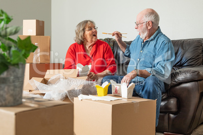 Senior Couple Enjoying Chinese Food Surrounded By Moving Boxes