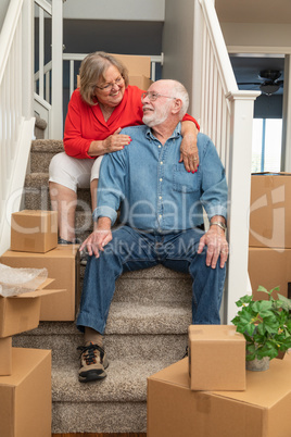 Senior Couple Resting On Stairs Surrounded By Moving Boxes