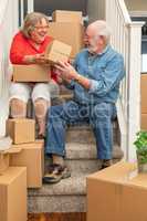 Senior Couple Resting On Stairs Surrounded By Moving Boxes