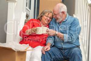 Tired Senior Adult Couple Resting on Stairs with Cups of Coffee