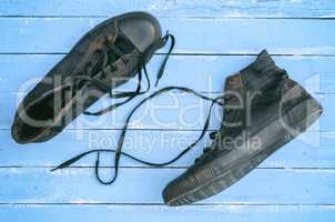 pair of black old shabby sneakers with loosened laces