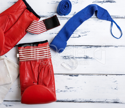 pair of leather red boxing gloves and blue bandage