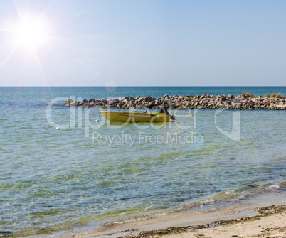 yellow boat with a motor at anchor near the shore