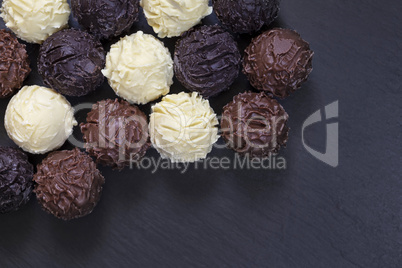 Truffles of fine chocolates on black stone background